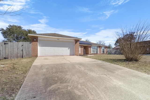 ranch-style house with a garage, a front yard, and solar panels