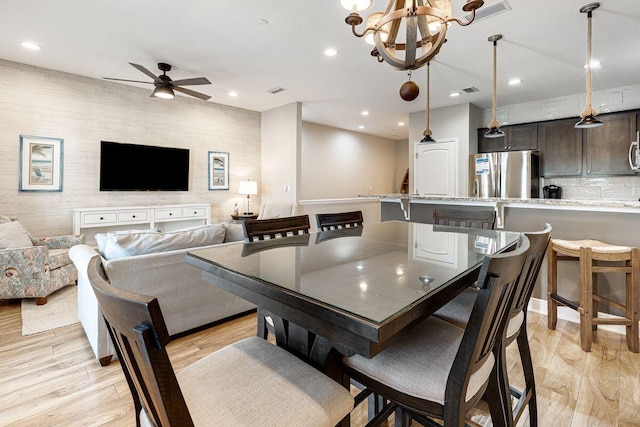 dining room featuring light wood-type flooring and ceiling fan with notable chandelier