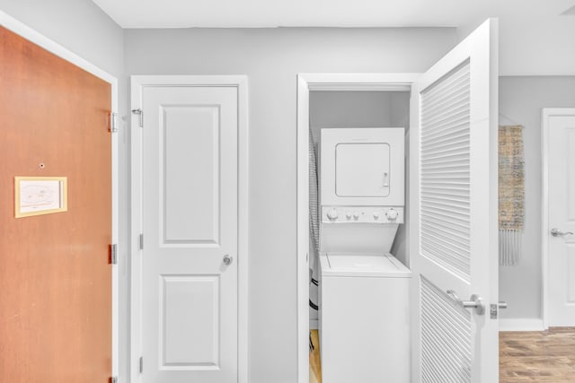 laundry area with light hardwood / wood-style flooring and stacked washing maching and dryer