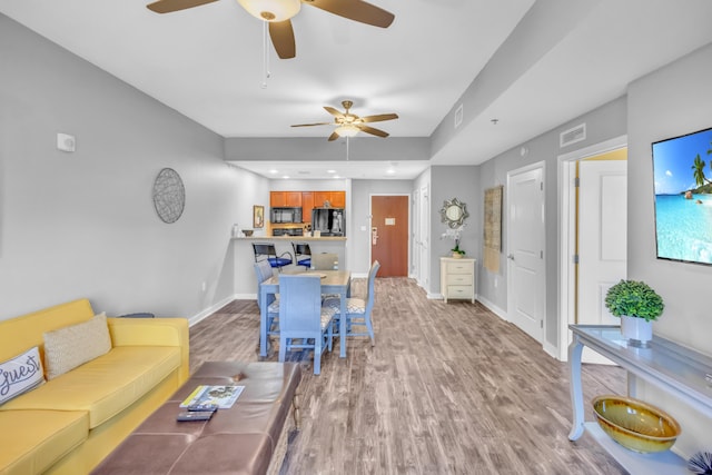 living room with ceiling fan and light hardwood / wood-style flooring