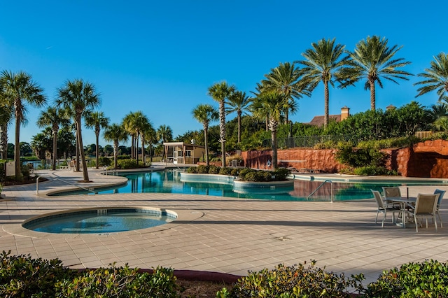 view of swimming pool featuring a hot tub and a patio area