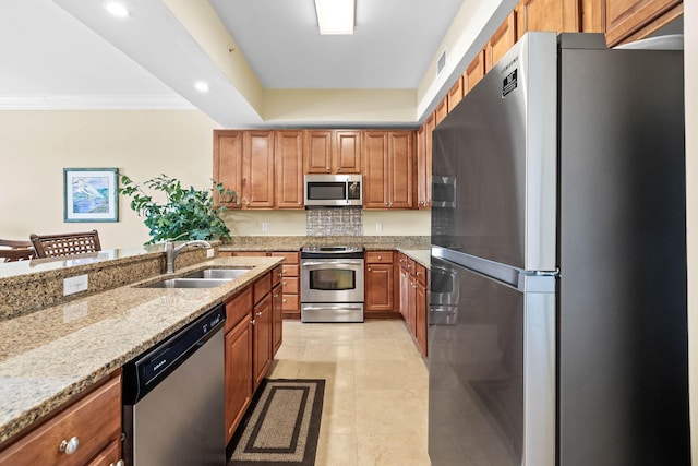 kitchen with light stone countertops, stainless steel appliances, sink, backsplash, and crown molding