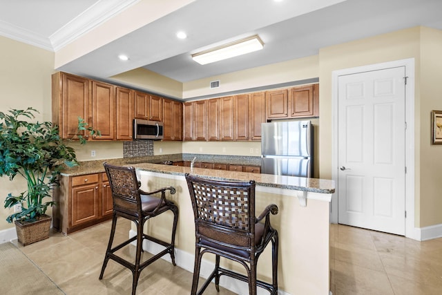 kitchen with stone countertops, appliances with stainless steel finishes, a breakfast bar area, and a kitchen island