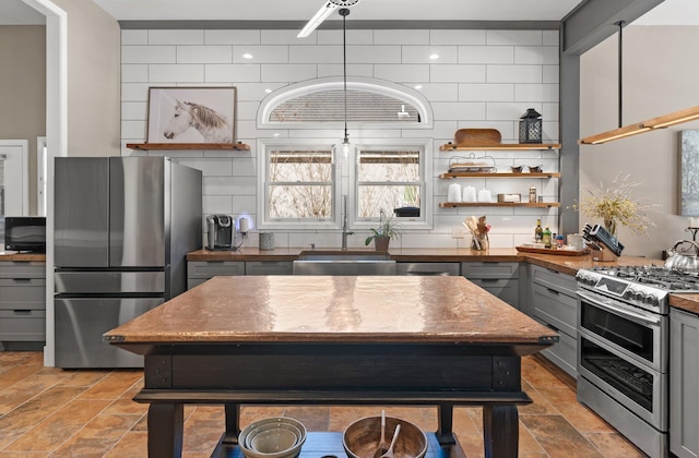 kitchen with gray cabinets, a kitchen island, appliances with stainless steel finishes, sink, and decorative backsplash