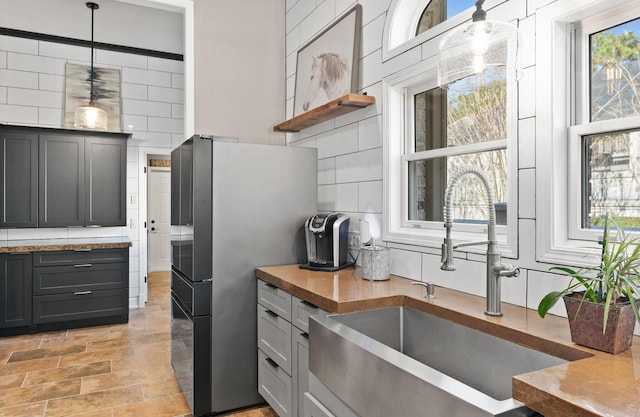 kitchen with stainless steel fridge, decorative light fixtures, sink, and gray cabinetry