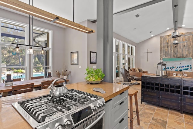 kitchen with white cabinetry, decorative light fixtures, high vaulted ceiling, and stainless steel gas stove