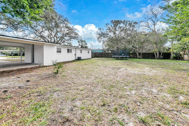 view of yard featuring a trampoline and a carport