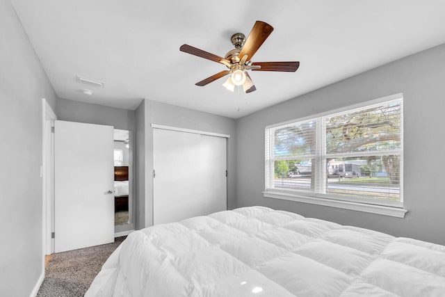 carpeted bedroom with ceiling fan and a closet