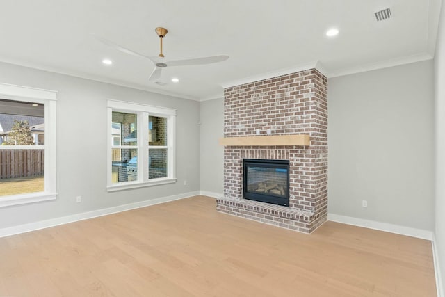 unfurnished living room with ceiling fan, light wood-type flooring, a fireplace, and crown molding