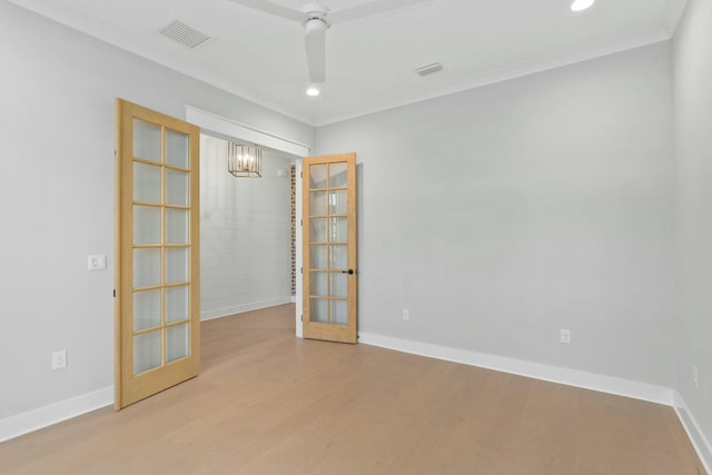 empty room featuring a chandelier, french doors, ornamental molding, and wood-type flooring