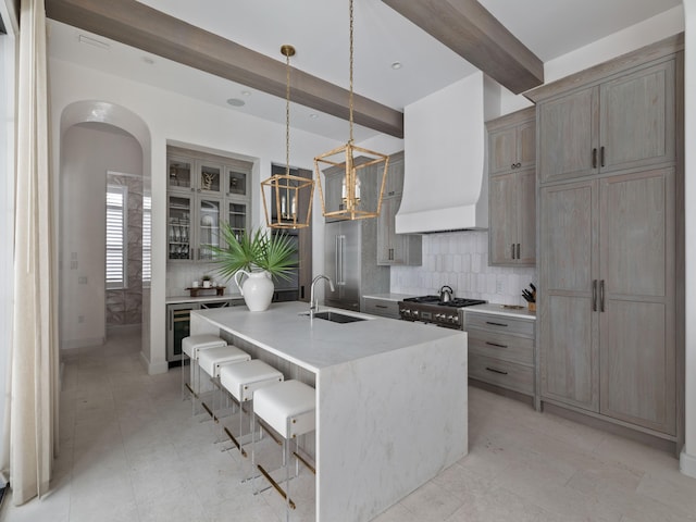 kitchen featuring pendant lighting, sink, beamed ceiling, an island with sink, and a kitchen breakfast bar