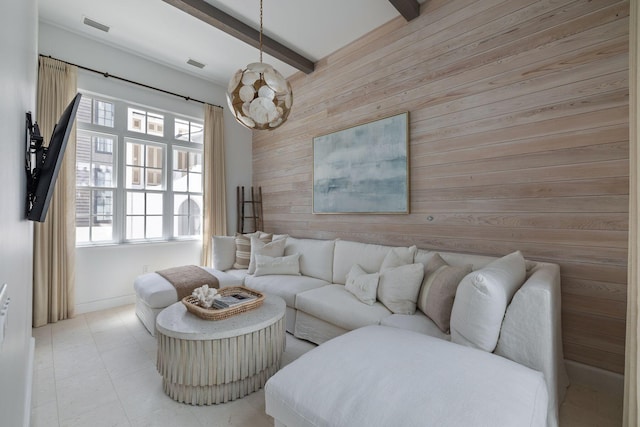 living room with plenty of natural light, beam ceiling, a notable chandelier, and wooden walls