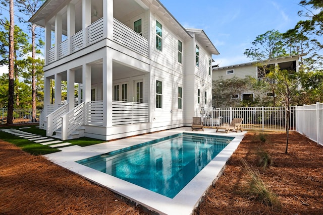 rear view of property featuring a balcony and a fenced in pool