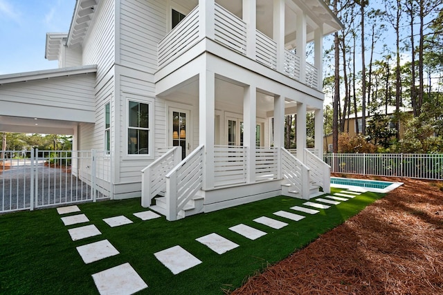 rear view of house with a lawn and a balcony