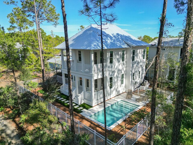 rear view of property featuring a covered pool, a patio area, and a balcony