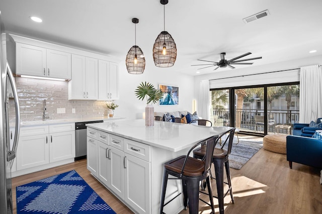 kitchen featuring decorative light fixtures, white cabinets, tasteful backsplash, and appliances with stainless steel finishes