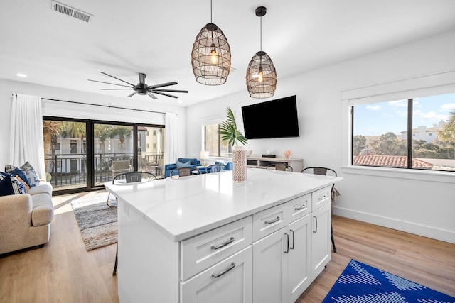 kitchen featuring ceiling fan, hanging light fixtures, white cabinets, and light wood-type flooring