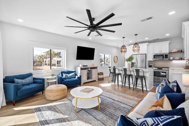 living room featuring light wood-type flooring and ceiling fan