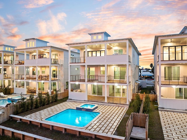 back house at dusk with a patio area and a swimming pool with hot tub