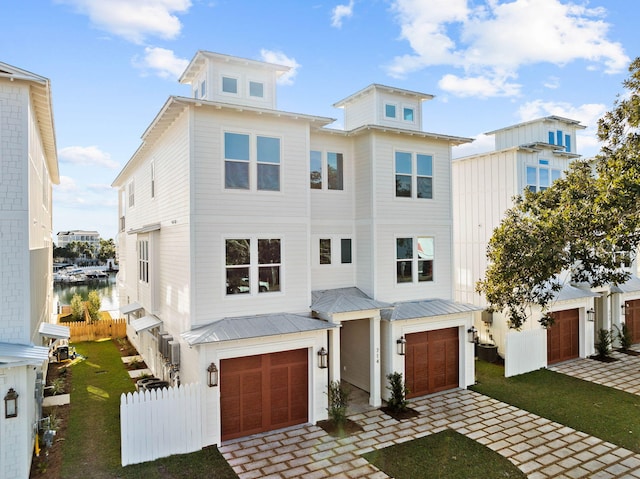 view of front of home with a garage, a front yard, and a water view