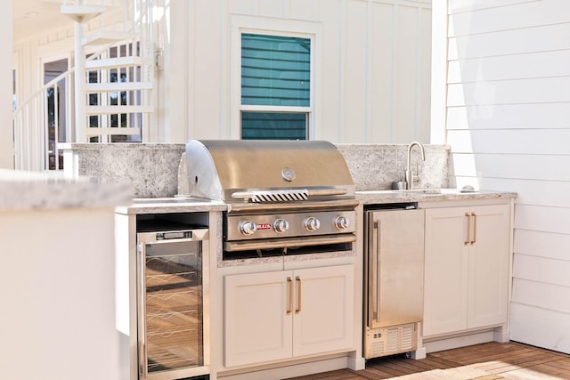 kitchen with beverage cooler, wooden walls, sink, light wood-type flooring, and fridge