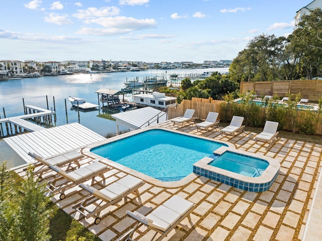 view of swimming pool with a patio area, a water view, and an in ground hot tub