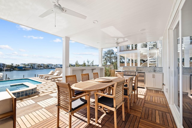 wooden deck with ceiling fan, a grill, area for grilling, and a water view