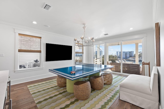 recreation room with an inviting chandelier, ornamental molding, and dark hardwood / wood-style floors