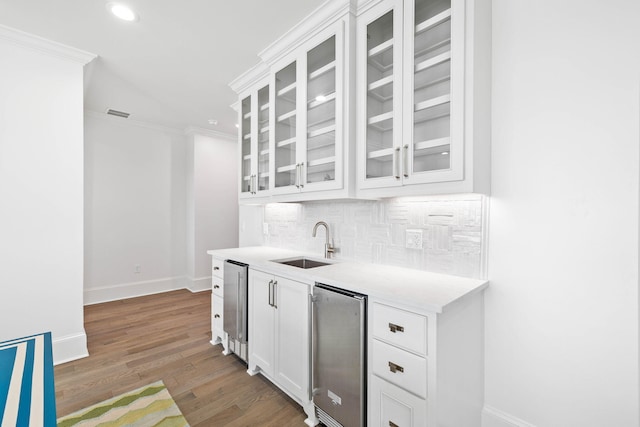 bar featuring dark wood-type flooring, sink, white cabinets, and crown molding