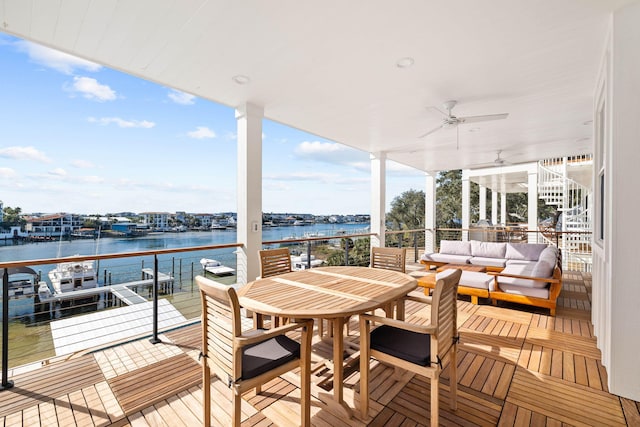 wooden deck with ceiling fan, an outdoor living space, and a water view