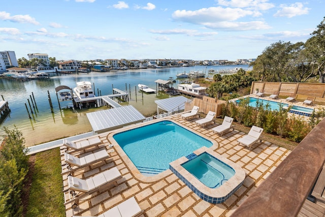 view of swimming pool with a patio, a water view, an in ground hot tub, and a boat dock