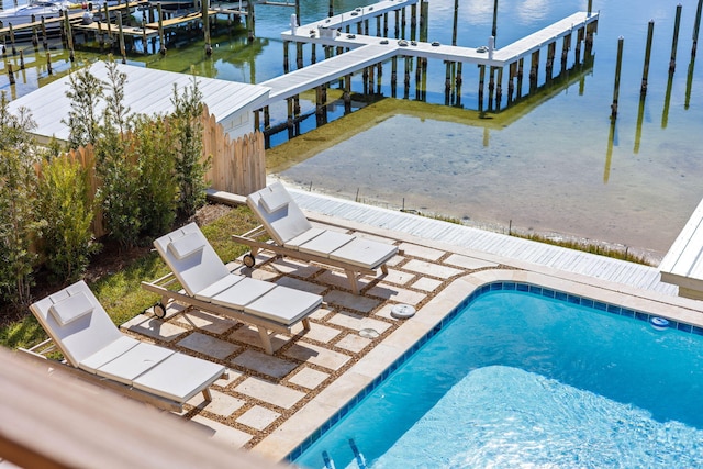 view of pool with a boat dock, a water view, and a patio