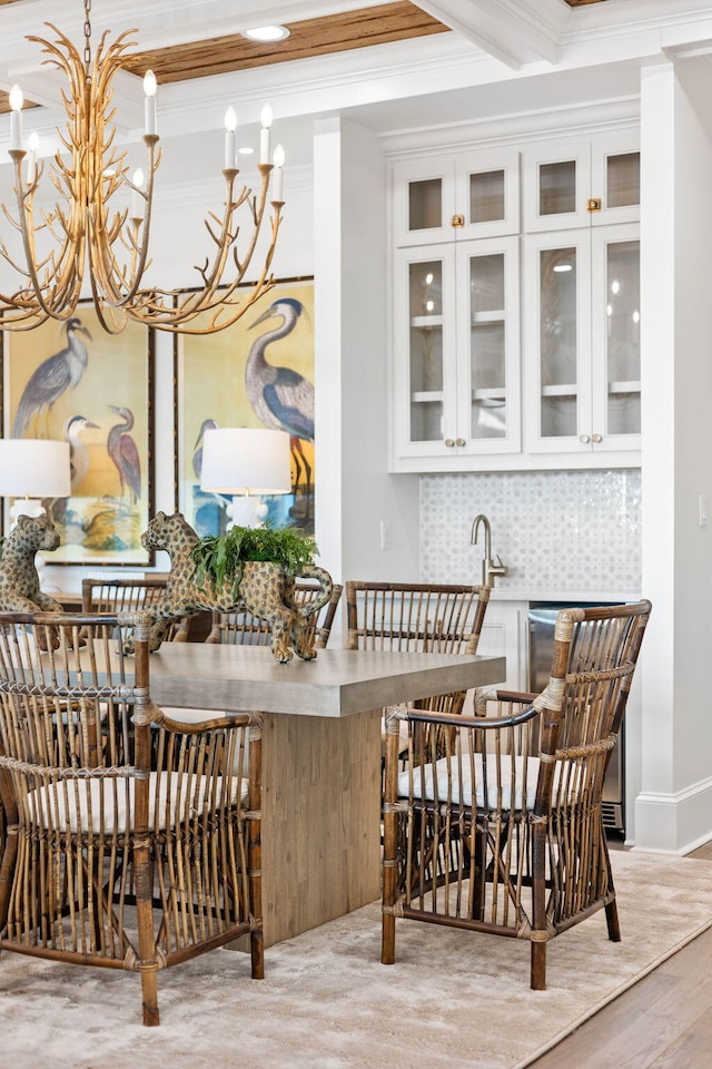 bar featuring backsplash, beam ceiling, an inviting chandelier, light wood-type flooring, and white cabinets