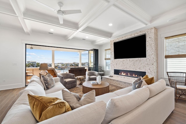 living room featuring coffered ceiling, ceiling fan, a large fireplace, wood-type flooring, and beamed ceiling