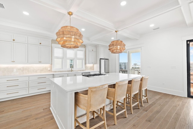 kitchen with pendant lighting, a kitchen island, light hardwood / wood-style flooring, appliances with stainless steel finishes, and white cabinets