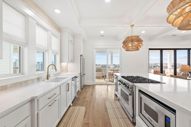 kitchen featuring appliances with stainless steel finishes, white cabinets, light stone counters, and sink