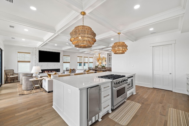 kitchen featuring white cabinetry, stainless steel range, a fireplace, a chandelier, and pendant lighting