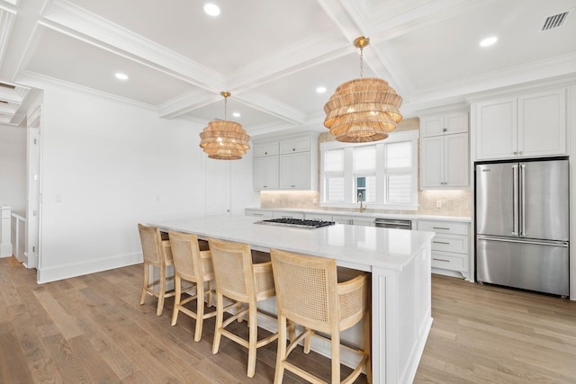 kitchen with appliances with stainless steel finishes, decorative light fixtures, white cabinets, a breakfast bar, and a center island