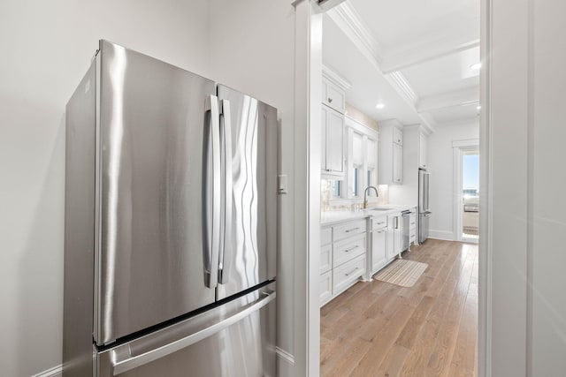 kitchen with white cabinets, stainless steel appliances, light hardwood / wood-style flooring, beam ceiling, and coffered ceiling