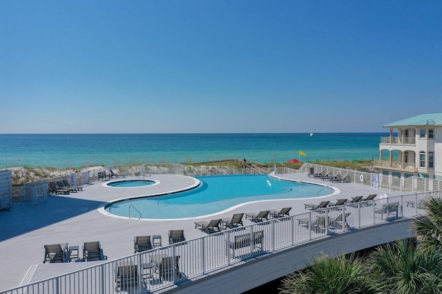 view of pool featuring a water view, a hot tub, and a patio area