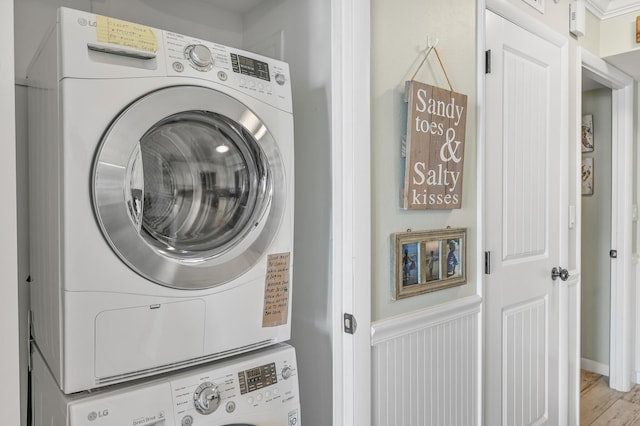 laundry room with stacked washer and clothes dryer and light hardwood / wood-style flooring