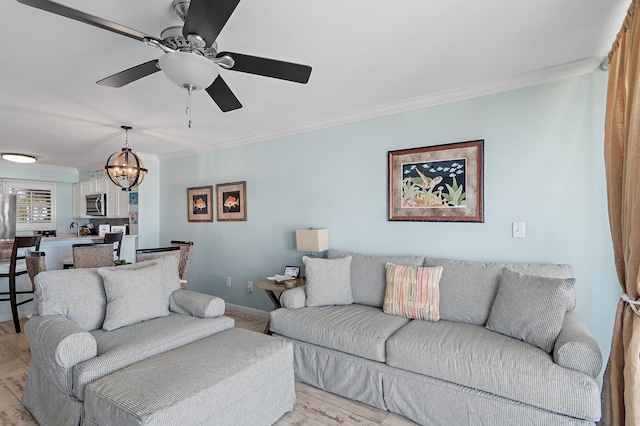 living room with light wood-type flooring, ornamental molding, ceiling fan with notable chandelier, and sink