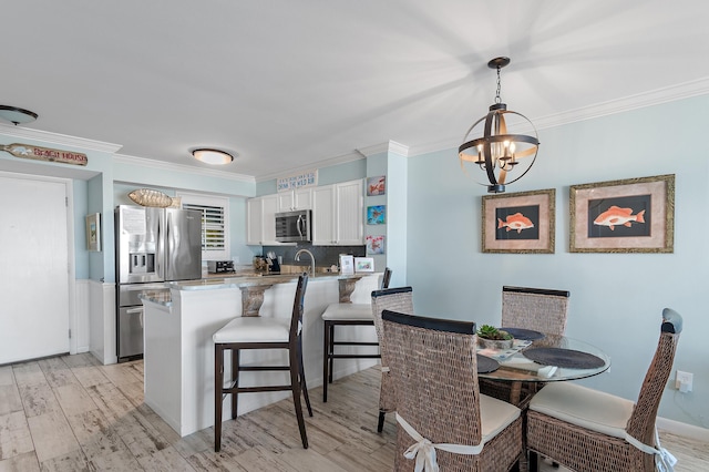 kitchen featuring kitchen peninsula, stainless steel appliances, a chandelier, pendant lighting, and white cabinets