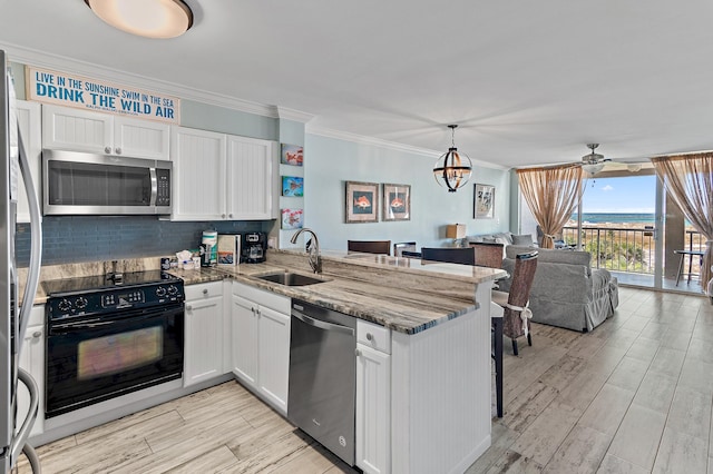 kitchen with white cabinetry, stainless steel appliances, dark stone counters, sink, and kitchen peninsula