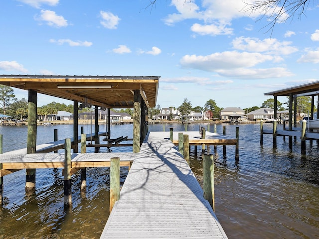 view of dock with a water view, boat lift, and a residential view