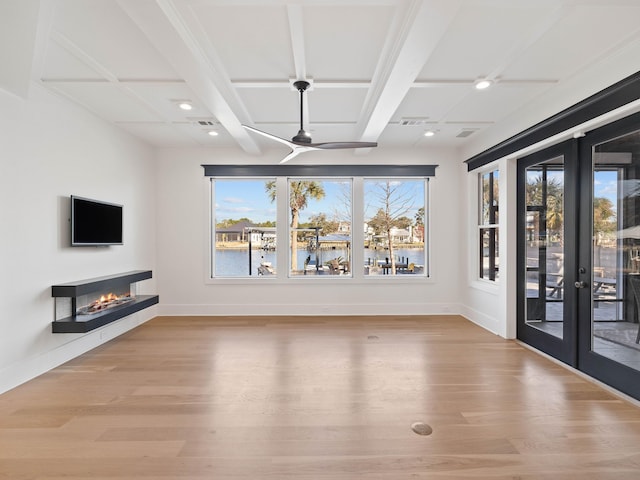 interior space with a glass covered fireplace, baseboards, coffered ceiling, and light wood finished floors