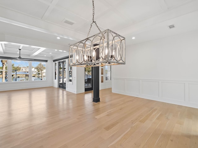 unfurnished dining area featuring beam ceiling, visible vents, a decorative wall, wood finished floors, and coffered ceiling