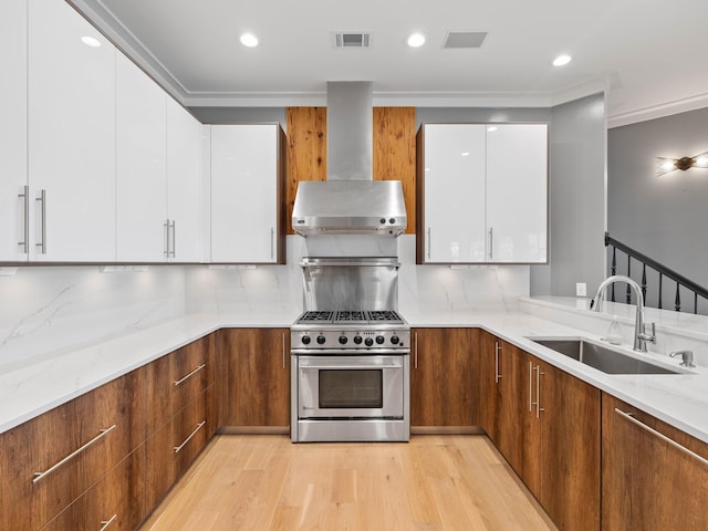 kitchen featuring range hood, white cabinetry, high end range, and a sink