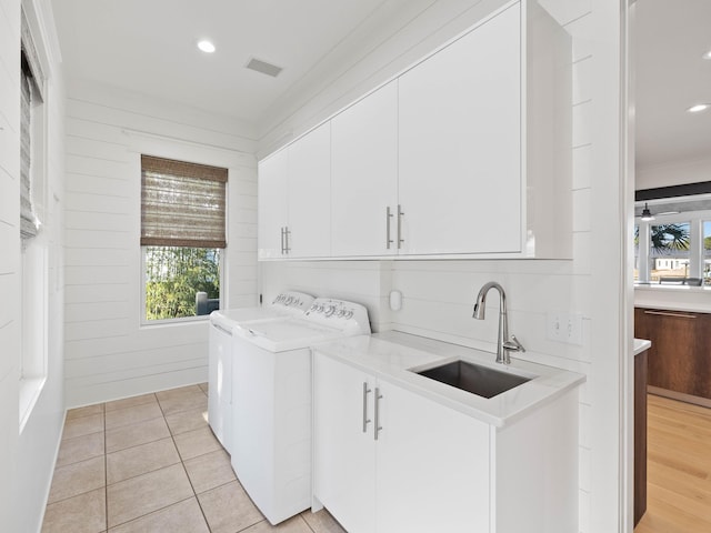 laundry room with washing machine and dryer, a sink, visible vents, cabinet space, and crown molding