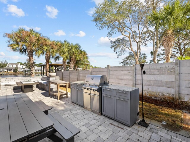 view of patio / terrace with a fenced backyard, a grill, an outdoor living space, and an outdoor kitchen